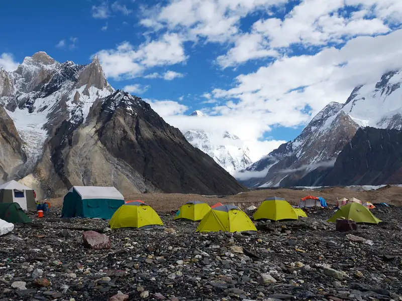 Basislager mit Zelten, umgeben von schneebedeckten Gipfeln und Gletschern.