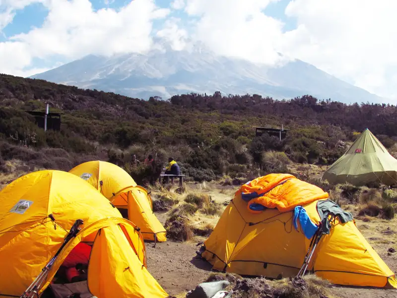 Basislager mit gelben Zelten und einem Berg im Hintergrund.