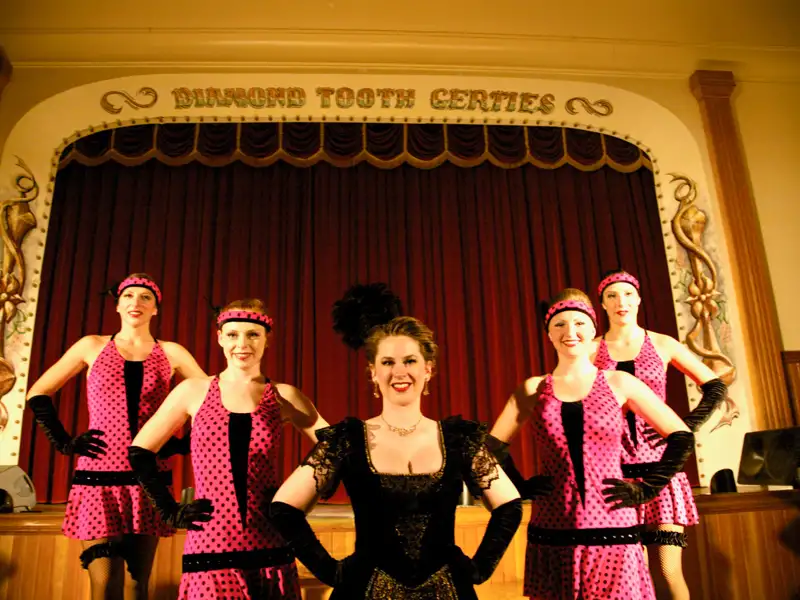 Tänzerinnen des Diamond Tooth Gerties in historischen Kostümen auf der Bühne.