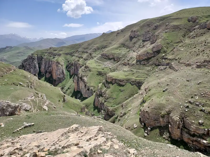 Steile Felswände und grüne Vegetation in einer Schlucht.