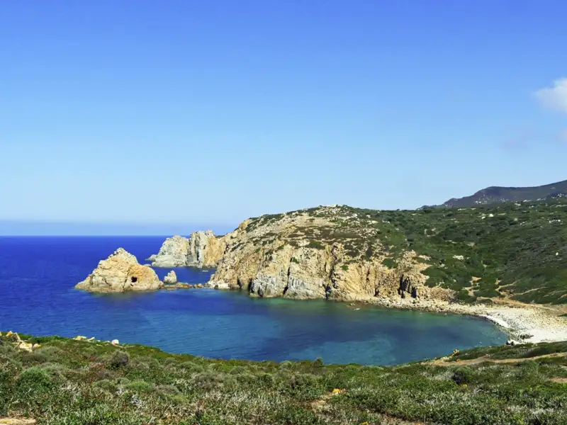 Felsige Küstenlandschaft mit einer kleinen Bucht und türkisfarbenem Wasser.