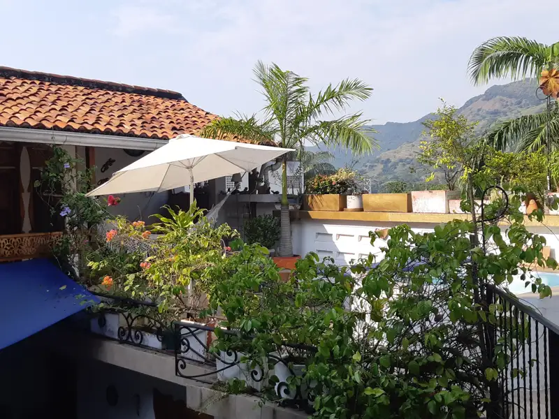 Terrasse mit Sonnenschirm, Pflanzen und Blick auf die Berge.
