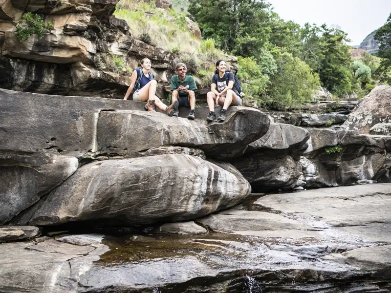 Wanderer ruhen sich während ihrer Wanderung auf Felsen an einem Fluss aus.