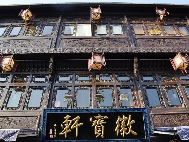 Fassade eines traditionellen chinesischen Gebäudes mit detaillierten Holzschnitzereien und hängenden Lampions.