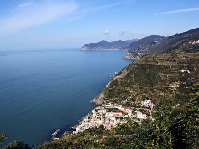 Panoramablick auf eine Küstenstadt an der italienischen Riviera, eingebettet zwischen bewaldeten Hügeln und dem Ligurischen Meer.