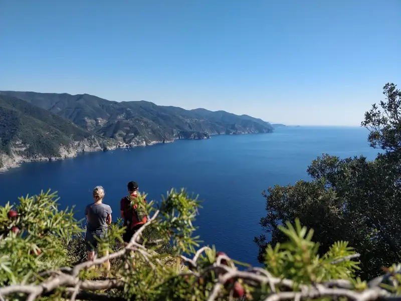 Zwei Wanderer auf einem Aussichtspunkt mit Blick auf das Meer und die Küste.