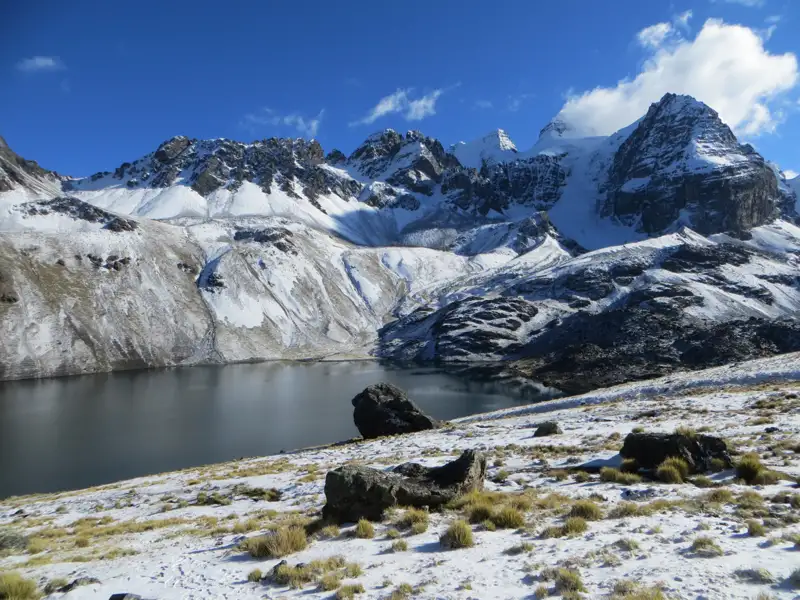 Bergsee mit schneebedeckten Bergen im Hintergrund.