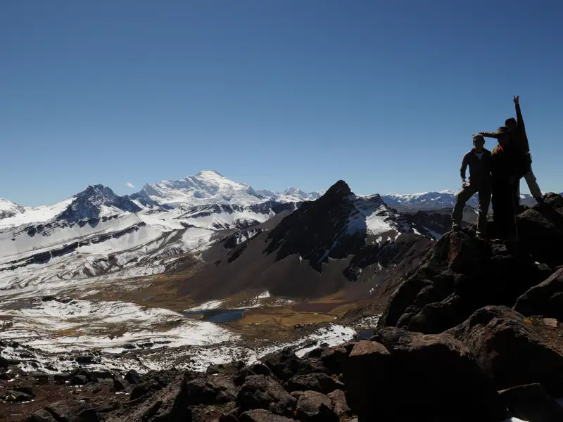 Wanderer auf einem Gipfel in den Anden mit Blick auf die umliegende Berglandschaft.