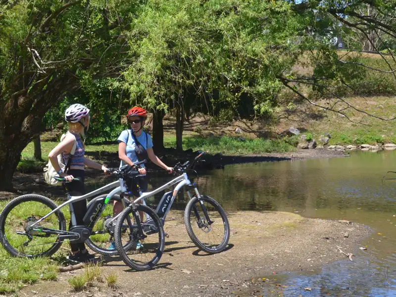 Zwei Radfahrerinnen pausieren während ihrer Radtour an einem See.