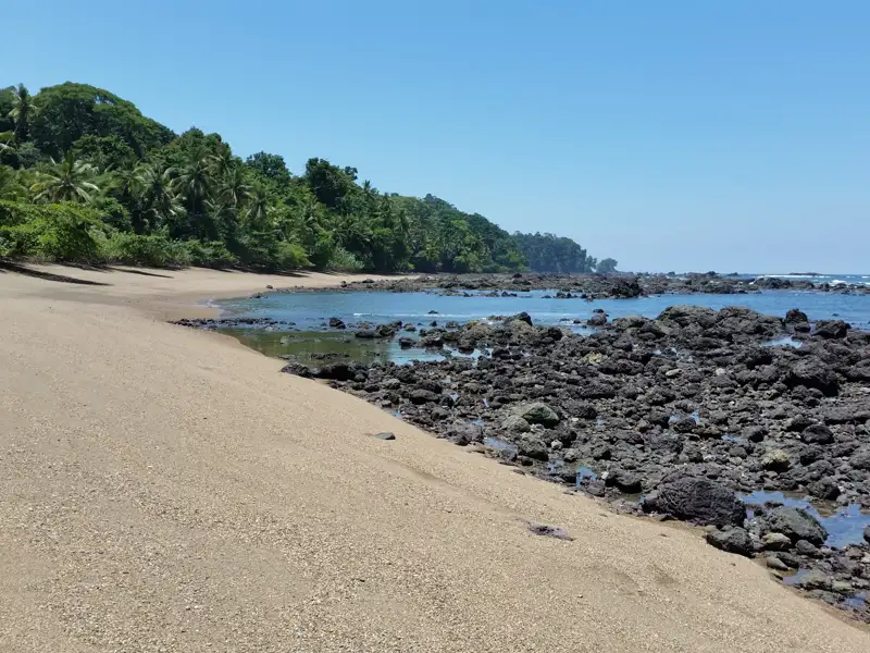 Küstenlandschaft mit Sandstrand und Felsen.