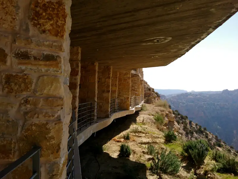Steinmauern und Betonüberdachung eines Gebäudes mit Blick auf eine Berglandschaft.