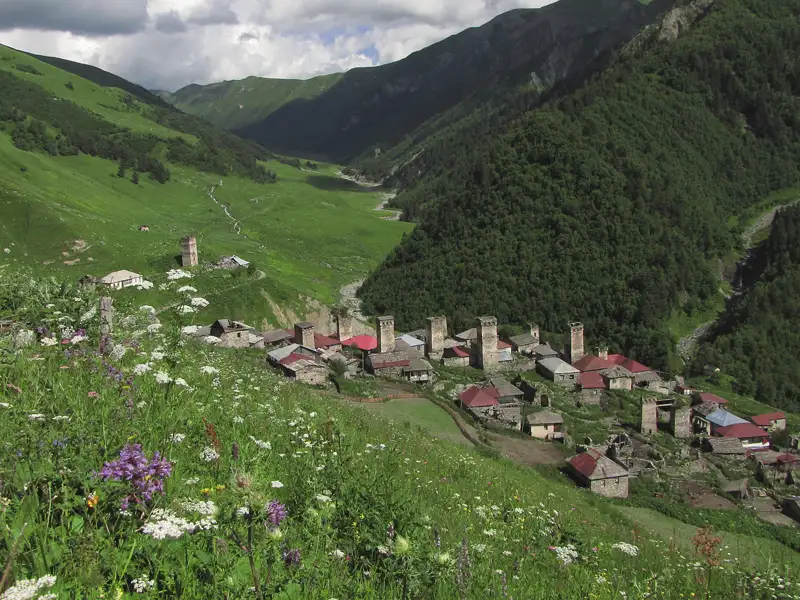 Traditionelles Bergdorf mit Wehrtürmen in einer idyllischen Berglandschaft.