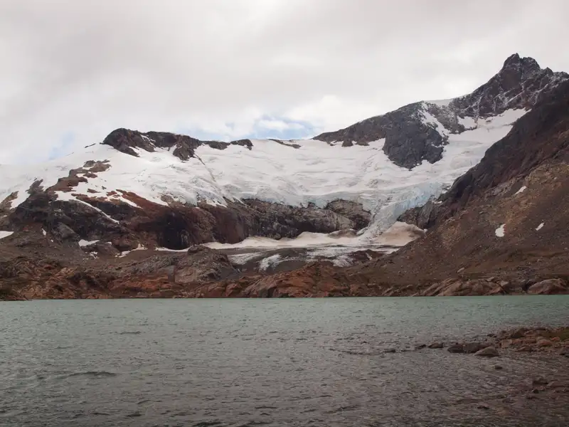 Blick auf einen Gletscher, der in einen Bergsee mündet.