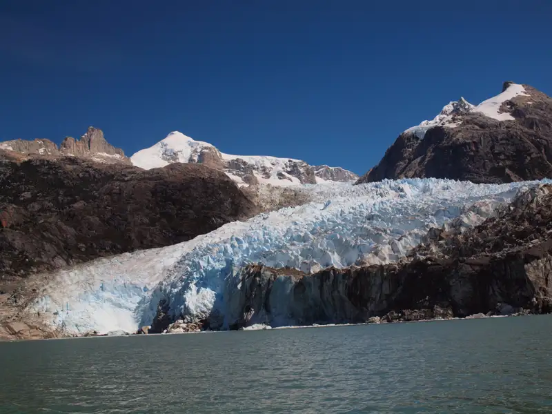 Beeindruckender Anblick eines Gletschers, der inmitten einer bergigen Landschaft ins Wasser kalbt.