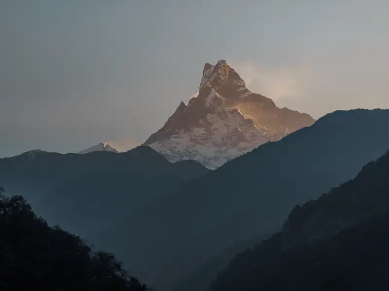 Schneebedeckter Berggipfel bei Sonnenaufgang.
