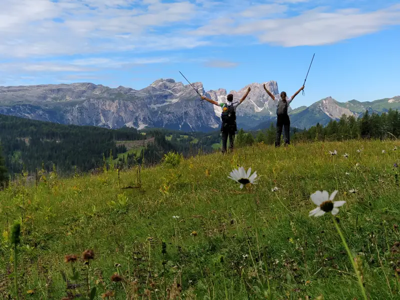Zwei Wanderer mit Wanderstöcken feiern das Erreichen eines Gipfels in den Bergen.