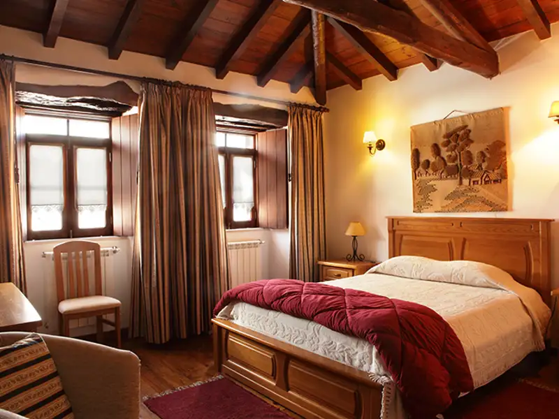 Holzbalkendecke und rustikales Schlafzimmer mit Holzmöbeln.