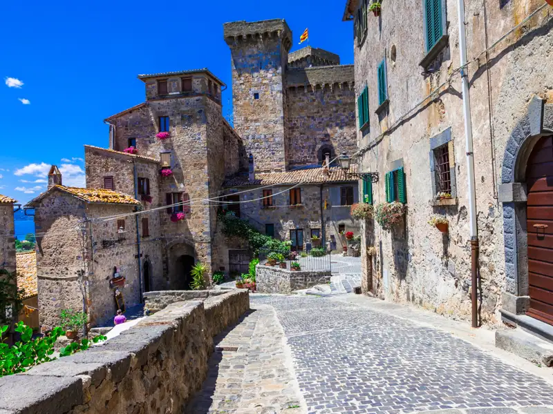Gepflasterte Straße und Steinhäuser in einem mittelalterlichen Dorf.