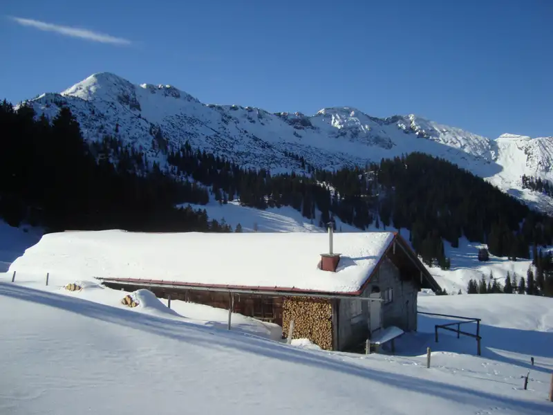 Alpenhütte im Winter mit Schnee bedeckt.