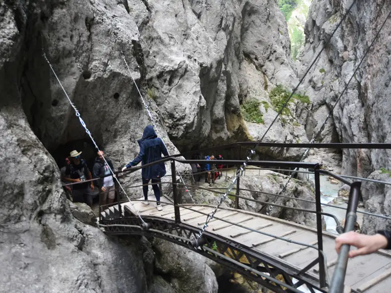 Hängebrücke in einer felsigen Schlucht mit Wanderern.