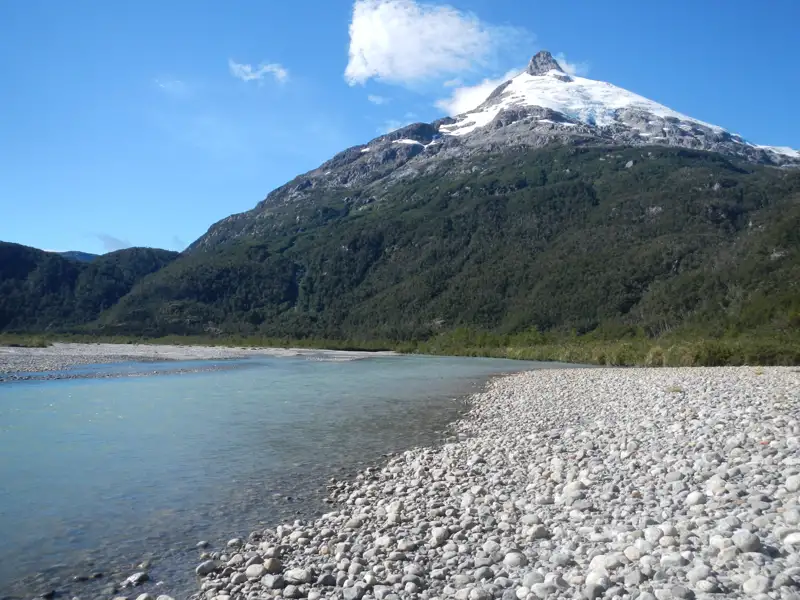 Szene mit einem Fluss und einem schneebedeckten Berg im Hintergrund.