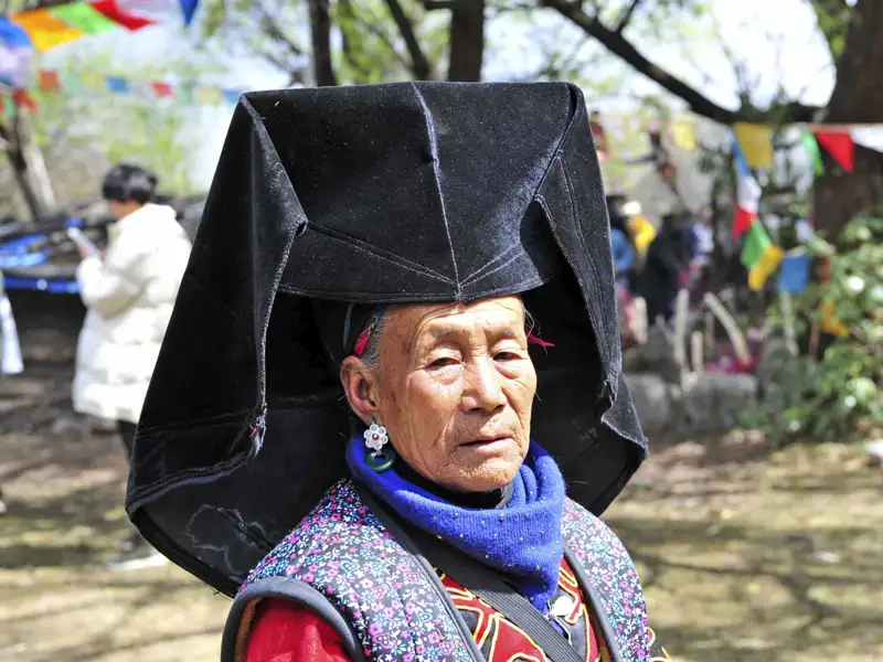 Frau mit traditionellem, schwarzem Kopfschmuck.