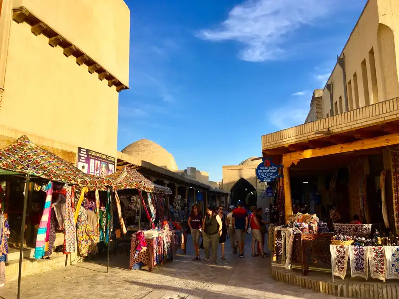 Bunte Marktstände mit traditioneller Kleidung und Souvenirs in Usbekistan.
