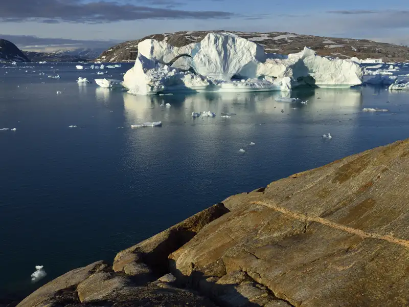 Eisberge im Meer, aufgenommen von einer felsigen Küste.