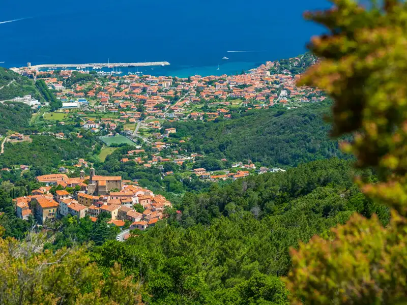 Panoramablick auf die Stadt an der Küste, umgeben von bewaldeten Hügeln und mit Blick auf das Meer.