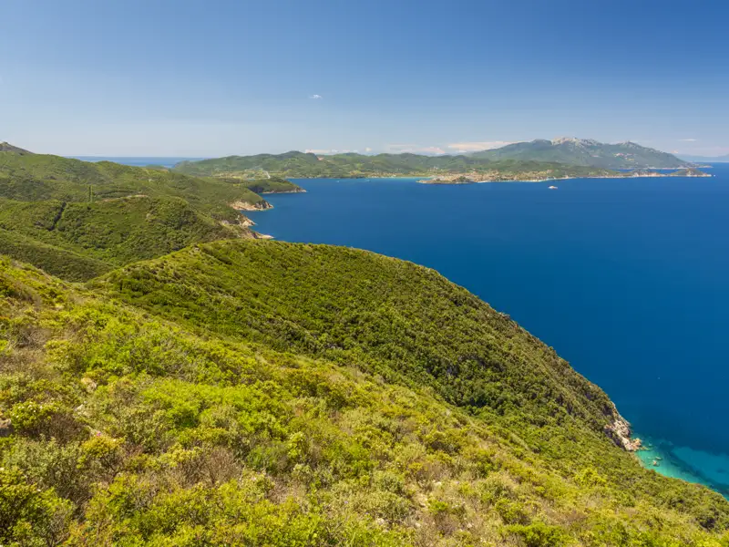 Blick auf die Küste mit grünen Hügeln und das blaue Meer.