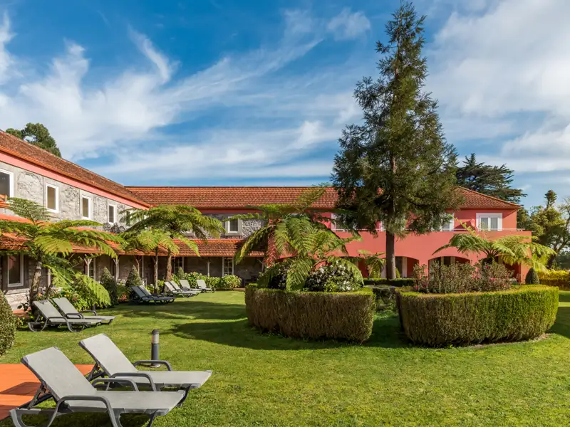 Hotelgarten mit Liegestühlen und Farnen.