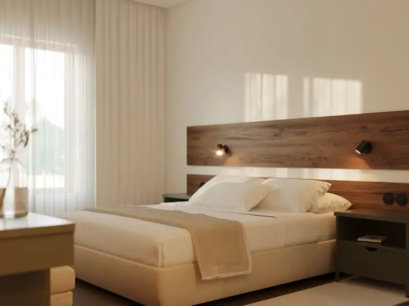 Doppelbett im Hotelzimmer mit Holz-Kopfteil und Nachttisch.