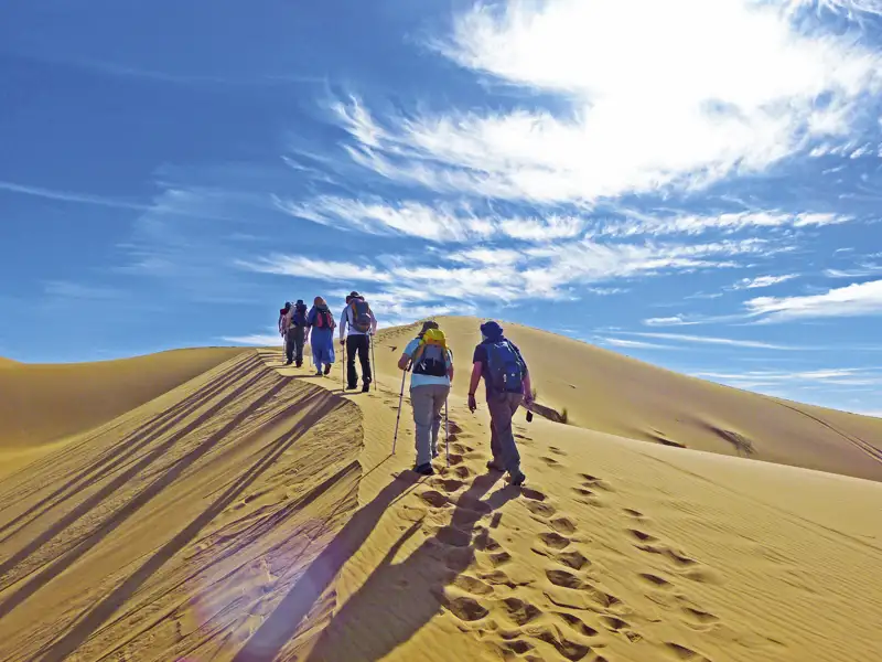 Wandergruppe besteigt eine Sanddüne.