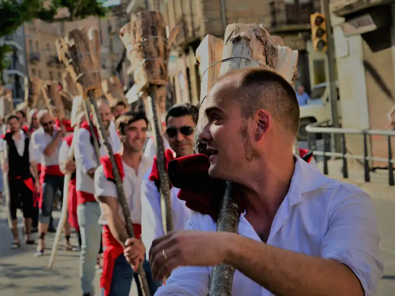Männer tragen Holzstangen, Teil einer traditionellen Veranstaltung.