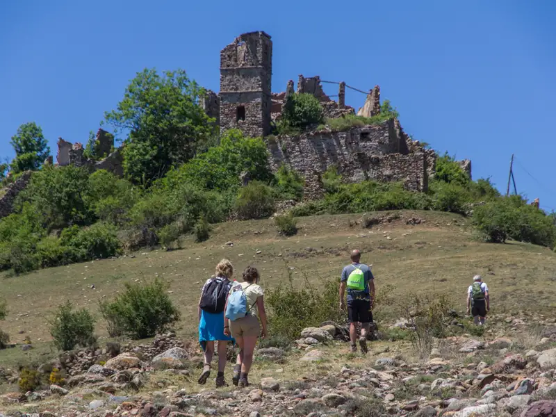 Wandergruppe besteigt den Hügel zu einer verfallenen Burg.