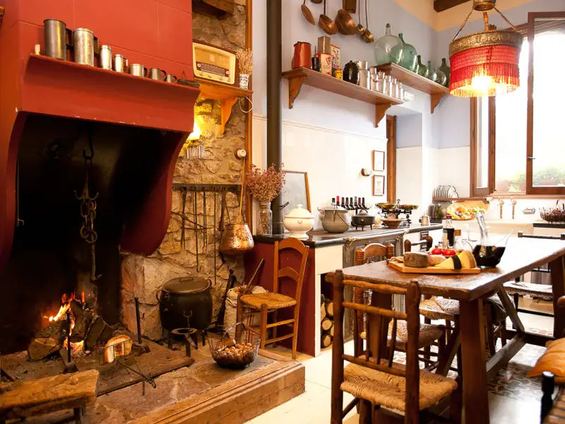 Rustikale Küche mit Kamin und traditionellen Kochutensilien.