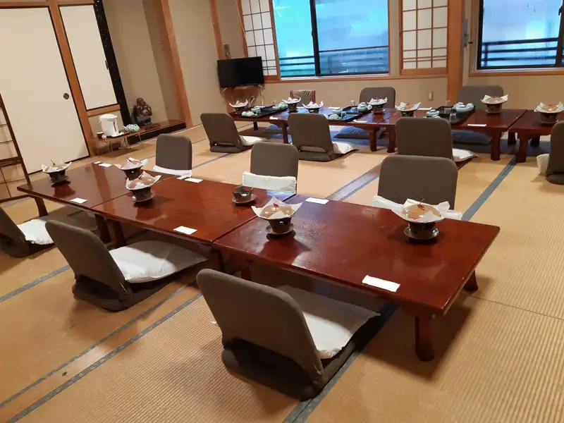 Speisesaal mit niedrigen Tischen und Sitzkissen, vorbereitet für eine Mahlzeit.