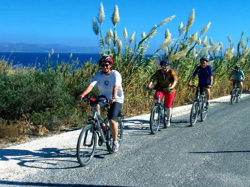 Radfahrer auf einer Küstenstraße mit Meerblick.