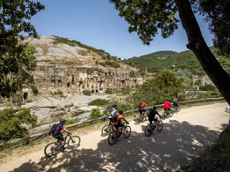 Mountainbiker auf einer Tour, die an historischen Ruinen vorbeiführt.