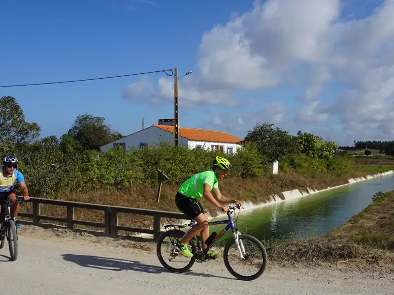 Radfahrer auf einer Radtour entlang eines Kanals in ländlicher Umgebung.