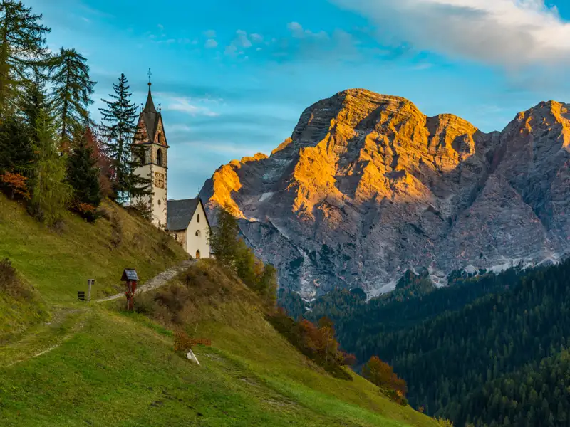 Kirche mit Bergkulisse im Abendlicht.