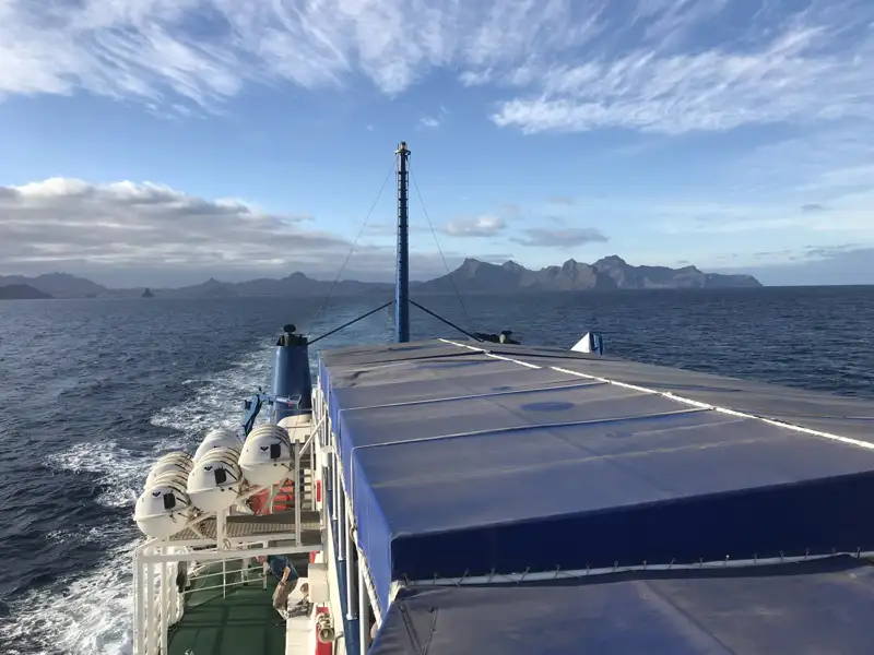 Blick vom Heck des Schiffes auf die bergige Küstenlinie.