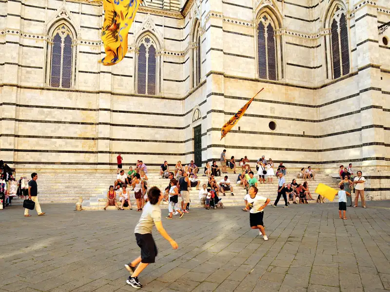 Kinder spielen mit Fahnen vor dem Dom.