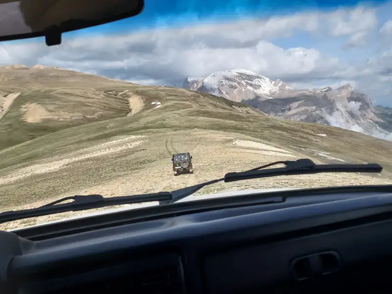 Fahrt im Geländewagen auf einer Bergstraße mit Blick auf einen schneebedeckten Gipfel.