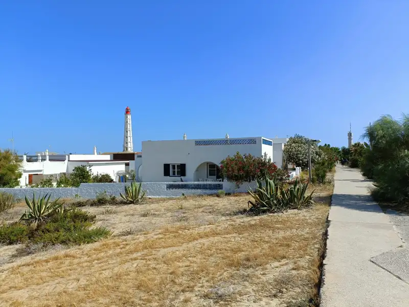 Weißes Haus in der Nähe eines Leuchtturms.