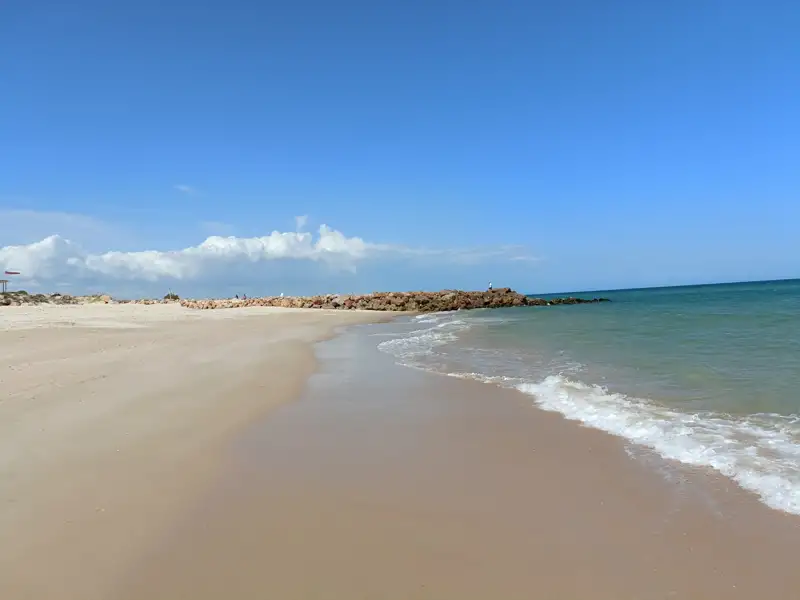 Strand mit Steinbuhne und leichtem Wellengang.