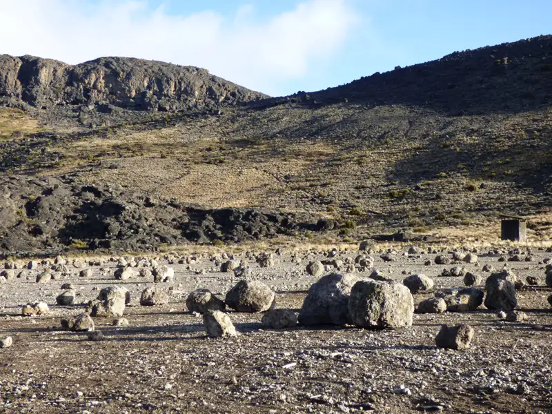 Felsige Landschaft mit verstreuten Steinen und einer Schutzhütte, typisch für die Region.