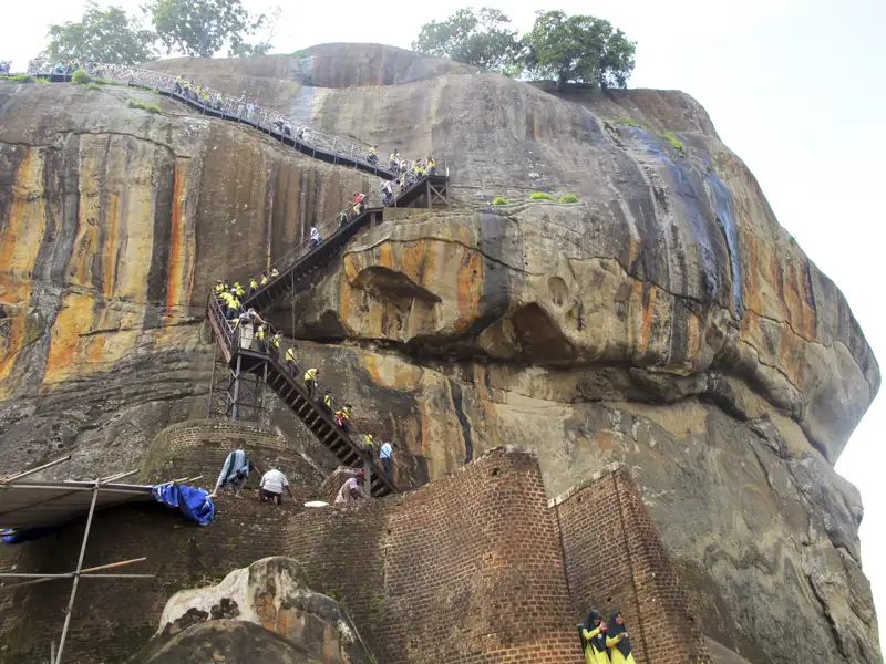 Besucher besteigen den Sigiriya Felsen über eine metallene Treppe.