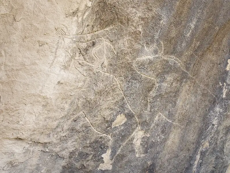 Historische Felsmalerei, die möglicherweise Tiere und menschliche Figuren darstellt.