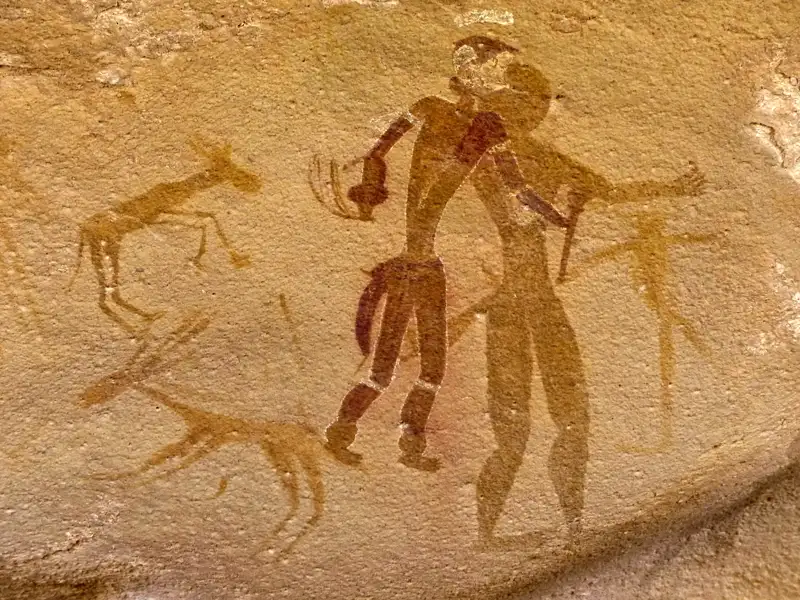 Historische Felsmalerei mit Darstellung von zwei menschlichen Figuren und mehreren Tieren, die wahrscheinlich Antilopen sind.